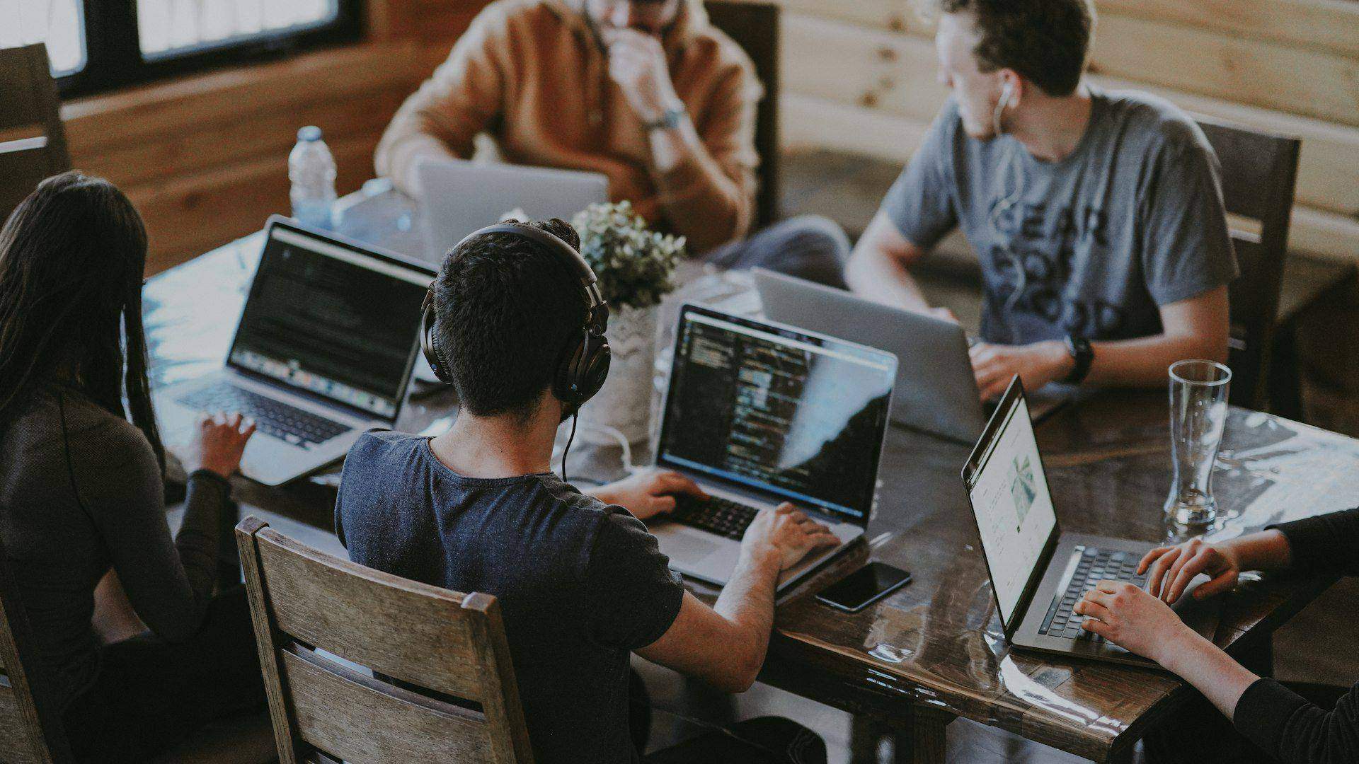 Young tech interns collaborating on code and software projects around a workspace desk